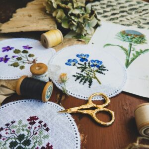 From above of assorted handmade embroidery made placed with threads and scissors for handicraft hobby